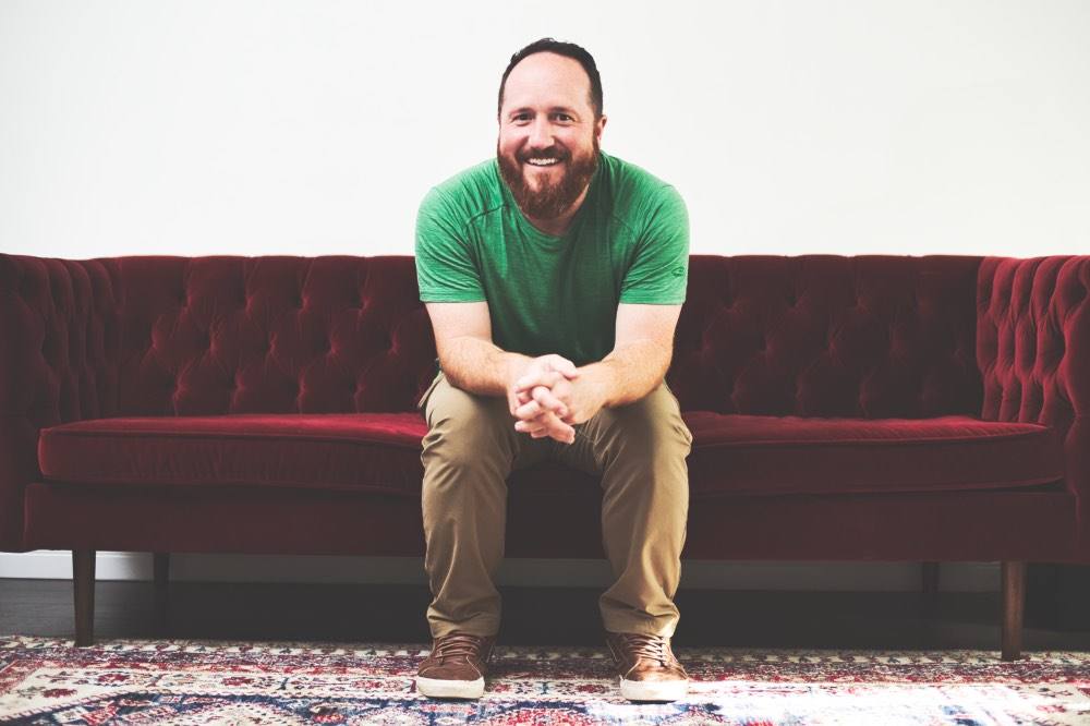 Our pastor, smiling, on a red velvet couch