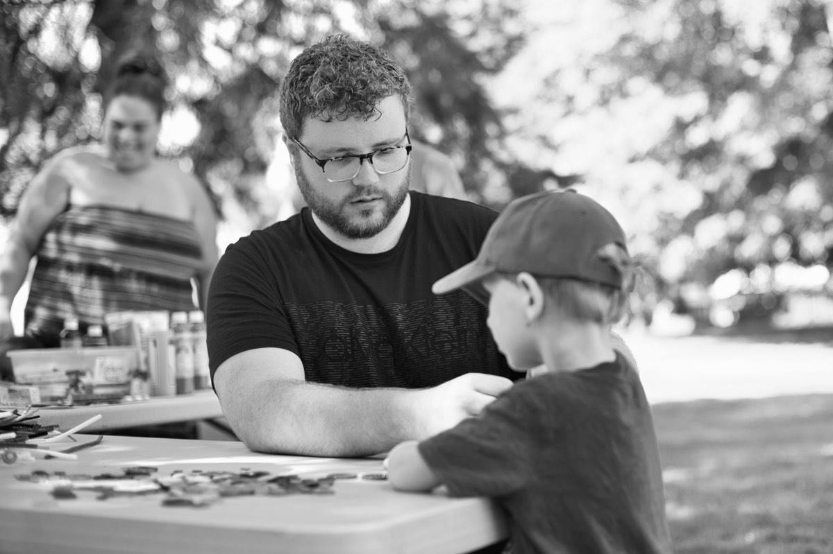 A young man and a boy working together at an outdoor table